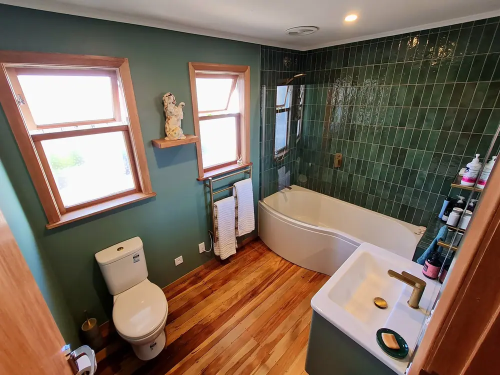 Green-tiled main bathroom renovation in Manawatu with stack-bond tiles, curved bath and native timber floor