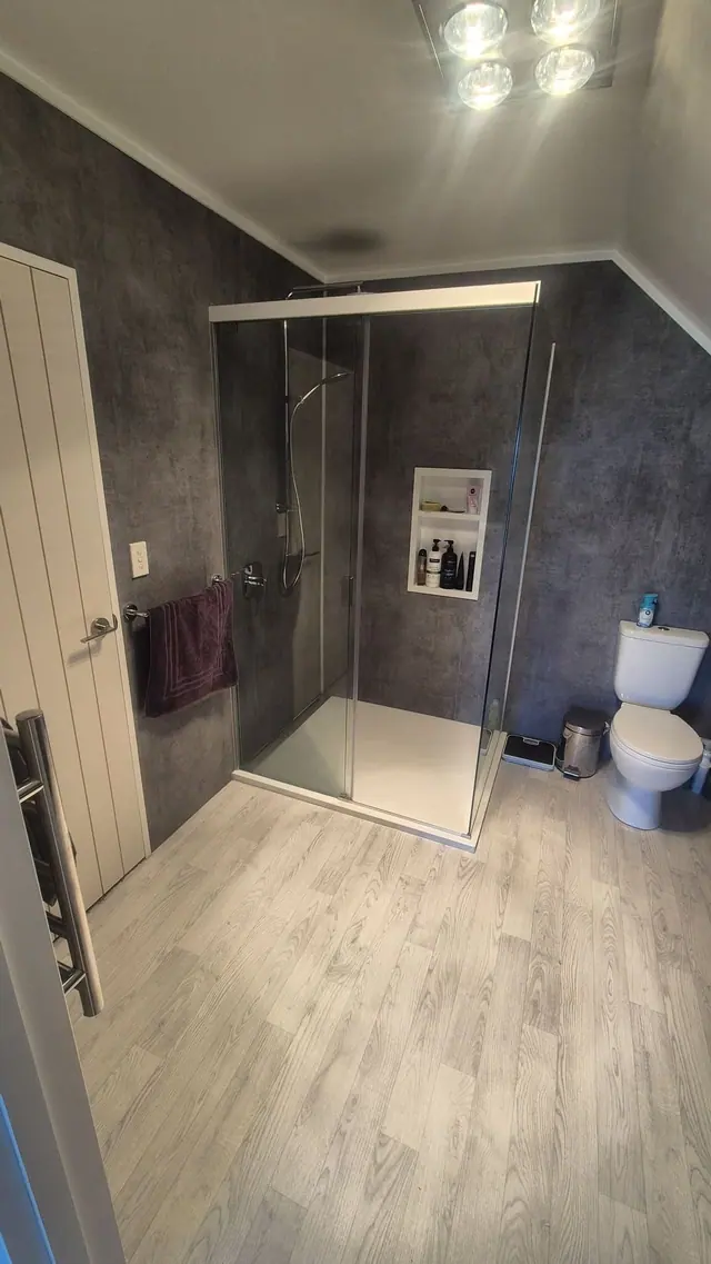 Compact upstairs bathroom with a sliding-door shower, recessed niche and heated towel rail