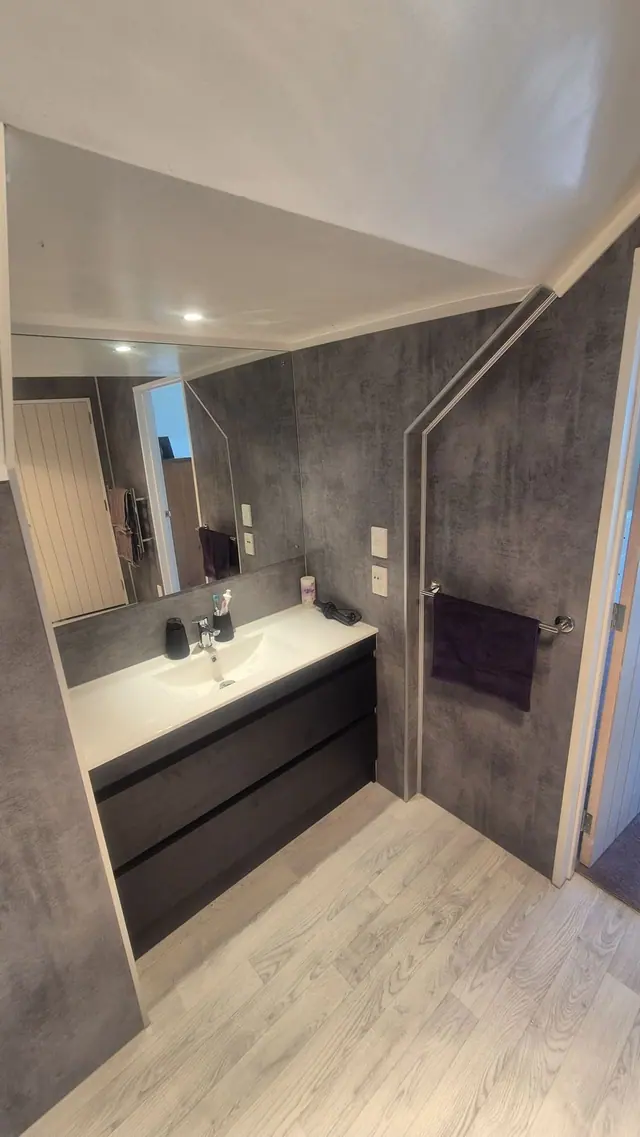 Upstairs bathroom renovation with a dark drawer vanity and concrete-look wall panelling
