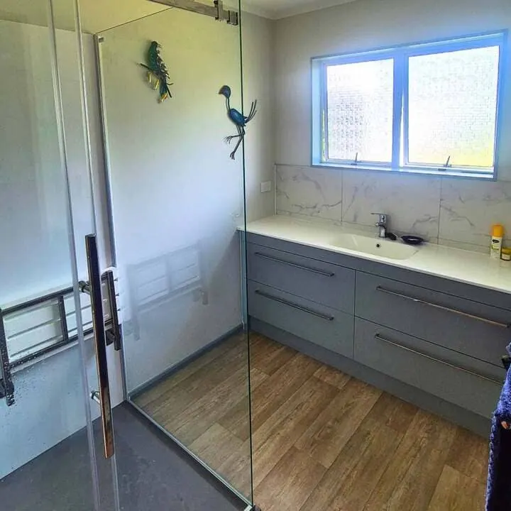 Ensuite with a hob-less walk-in shower, full-height glass panel and vanity under the window